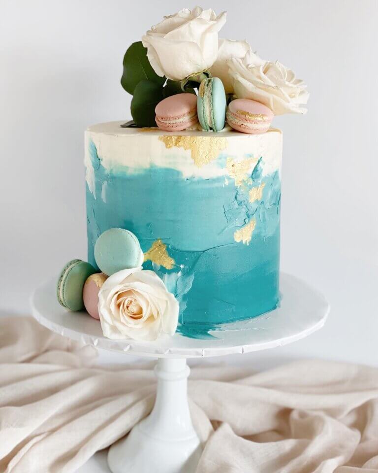 Teal ombre cake with macarons and flowers.